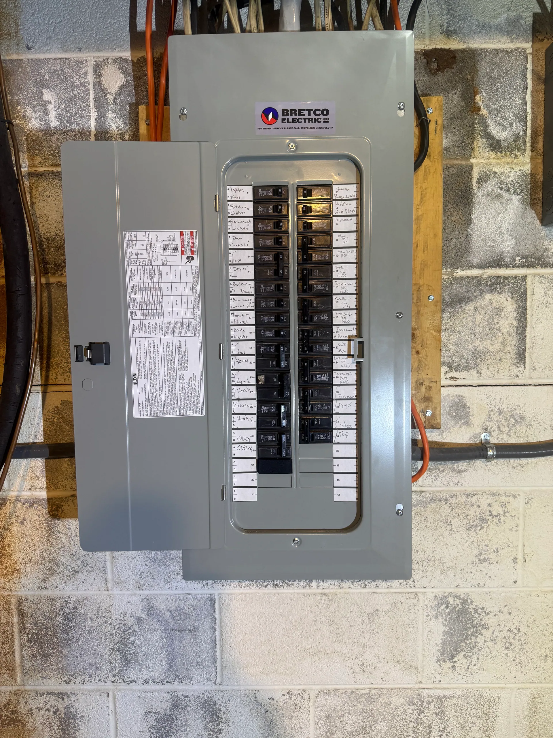 Bretco Electric labeled breaker panel open door cinder block