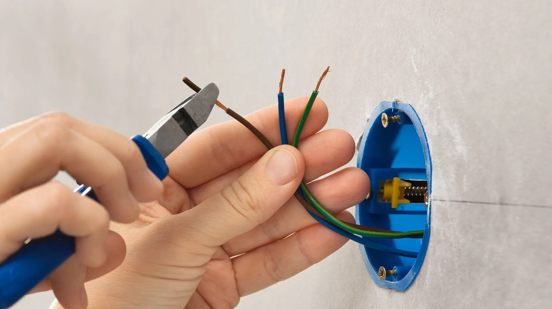 Electrician cutting wires blue outlet box