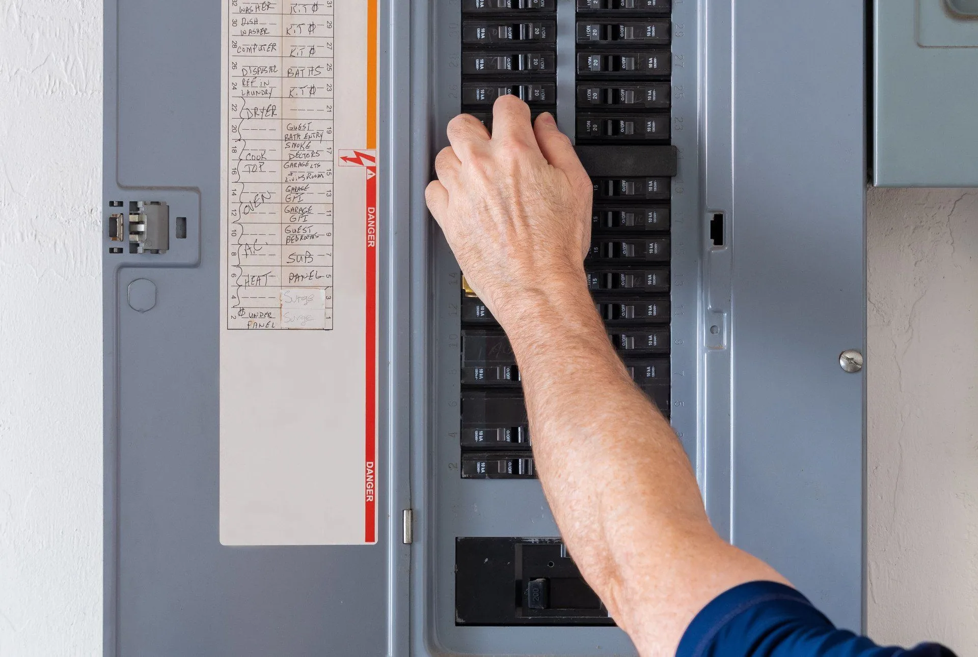 Hand flipping breaker labeled circuit panel