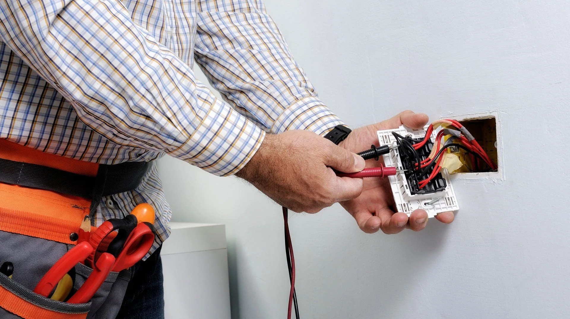 Plaid shirt electrician tool belt probing switch plate